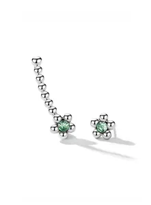 Détail macro de boucles d'oreilles fleurs asymétriques en argent S925 et zircon vert