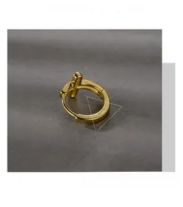 Vue macro de la boucle d'oreille en argent S925 doré avec un pendentif en croix