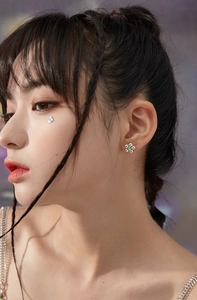Gros plan d'une boucle d'oreille fleur avec pierre verte portée par un mannequin