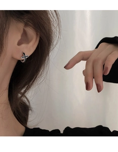 Gros plan d'un modèle portant une créole en argent avec pendentif croix noire