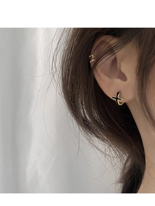 Gros plan sur boucle d'oreille anneau doré avec croix noire et manchette d'oreille double