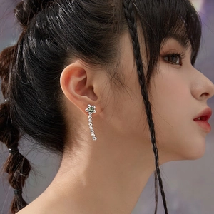 Boucles d'oreilles fleur argentée avec zircons verts portées par un mannequin asiatique