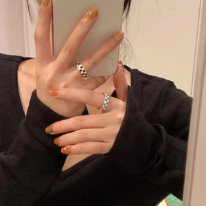 Detailed view of fashionable black, white and blue checkered enamel open rings on finger