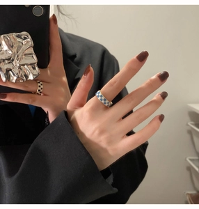 Detailed close-up of checkerboard enamel rings in blue and black on model fingers