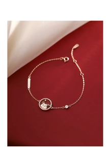 Macro detail of rose gold tiger pendant bracelet with lucky tag on red leather
