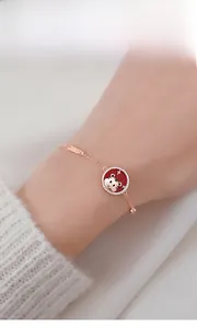 Detail of rose gold tiger bracelet with lucky charm on model's wrist in soft light