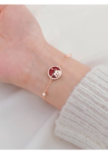 Detail of tiger charm bracelet with red enamel and crystals on a gold chain