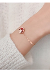 Detailed close-up of rose gold tiger bracelet with red pendant and Lucky tag