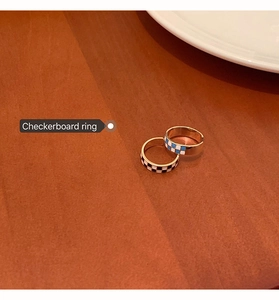 Detail view of gold checkerboard open rings in black-white and blue-white enamel finish