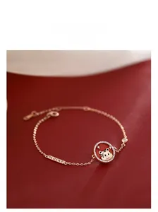 Detail of rose gold bracelet featuring lucky tiger charm and engraved lucky tag