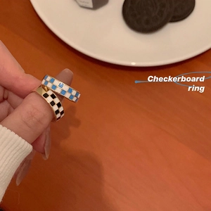 Detail of gold-trimmed checkerboard rings in blue and black enamel on wood background