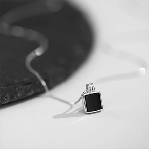 Vue macro d'un pendentif carré minimaliste en argent avec incrustation en émail noir poli