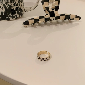 Detail of checkered enamel open ring with adjustable band and classic black white pattern