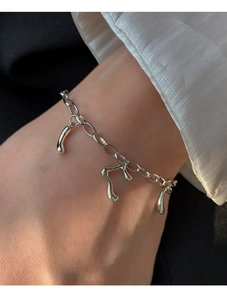 Détail de breloques irrégulières en métal liquide sur un bracelet à maillons argenté