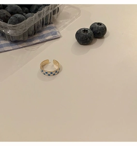 Detail view of a gold checkerboard open ring with blue and white enamel pattern