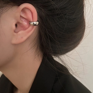 Close-up of minimalist silver ear cuff on ear with a polished mirror finish surface
