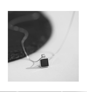 Détail d'un collier pendentif carré noir en onyx avec une fine chaîne en argent