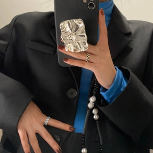 Silver irregular crumpled metal phone griptok on black case held by hand fashion accessory