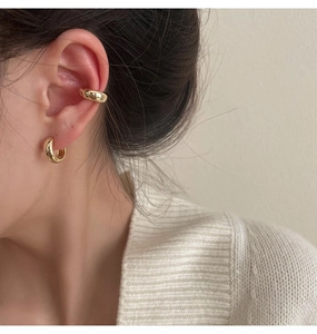 Close-up of minimalist gold metal ear cuff and matching earrings worn by a model
