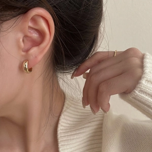 Close-up of polished gold hoop ear cuff on model with a minimalist luxury style