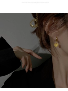 Détail de boucles d'oreilles cœur vintage doré au fini sablé portées par un mannequin