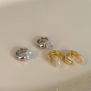 Detailed macro view of minimalist gold and silver C-shaped ear clips with soft silicone pads