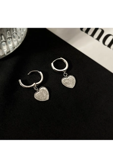 Gros plan détaillé de boucles d'oreilles cœur en argent S925 avec fini sablé brillant