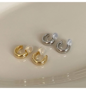 Detail of U-shaped gold and silver clip-on earrings with clear silicone comfort pads