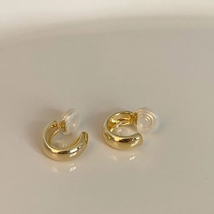 Close-up of golden C-shaped clip-on earrings with comfortable silicone pads
