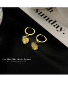 Gros plan de boucles d'oreilles cœur dorées avec texture sablée et poinçon S925