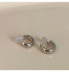 Close-up of silver C-shaped clip-on earring with transparent silicone comfort pad