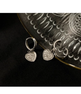 Gros plan de boucles d'oreilles cœur en argent S925 avec texture scintillante