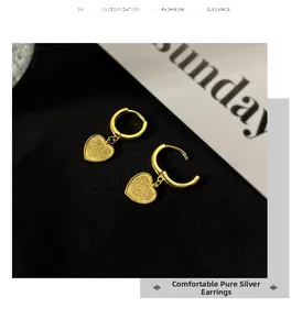 Détail de boucles d'oreilles cœur vintage en argent doré avec une finition mate texturée