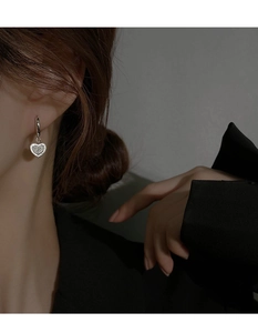 Détail de boucles d'oreilles cœur étincelantes avec zircons portées par un mannequin