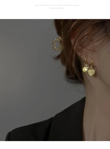Gros plan de boucles d'oreilles cœur vintage dorées texturées portées par un mannequin