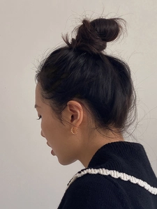 Close-up of 18K gold twisted hoop earrings worn on earlobe for minimalist style