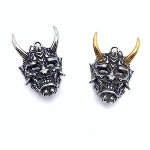 Détail des pendentifs masque Hannya en finitions argent et or avec texture vintage