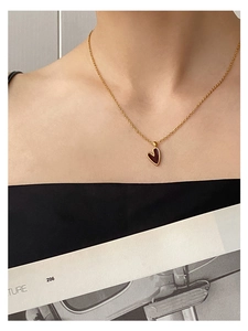 Nahaufnahme einer Vintage-Goldkette mit dunkelrotem Herzanhänger an einem Modell