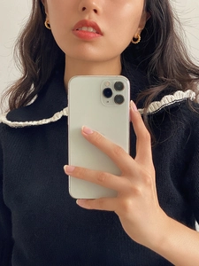 Close-up of golden twisted rope hoop earrings worn by a model in a minimalist style