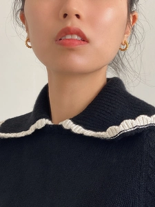 Close-up of golden twisted rope hoop earrings worn by a model in a minimalist style