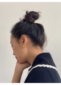 Close-up of golden twisted rope hoop earrings worn by a model for a stylish look