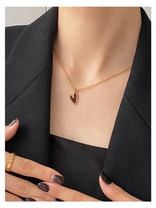 Nahaufnahme einer minimalistischen Goldkette mit Herzanhänger und gewelltem Ring