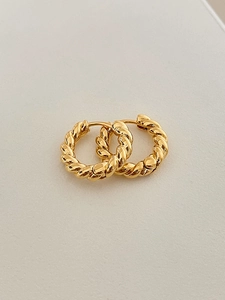 Close-up of golden twisted rope hoop earrings with elegant spiral texture and metallic shine