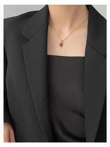 Detail einer minimalistischen Herz-Halskette in Gold an einem Model in schwarzem Blazer