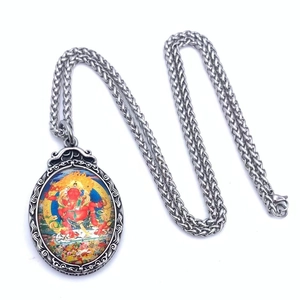 Gros plan d'un collier en acier titane vintage avec pendentif de divinité Thangka rouge