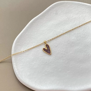 Minimalistische S925 Silber Goldkette mit weinrotem Herzanhänger auf einem Keramikteller