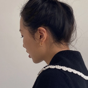 Elegant gold twisted rope hoop earrings for women worn by a model in a close-up profile view