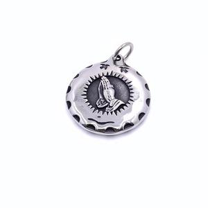 Detailed macro view of vintage titanium steel praying hands pendant with oxidized silver finish