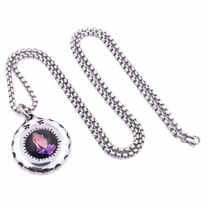 Detailed macro of a stainless steel box chain and religious praying hands pendant necklace