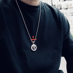 Detail of silver titanium steel necklace with praying hands pendant on black t-shirt